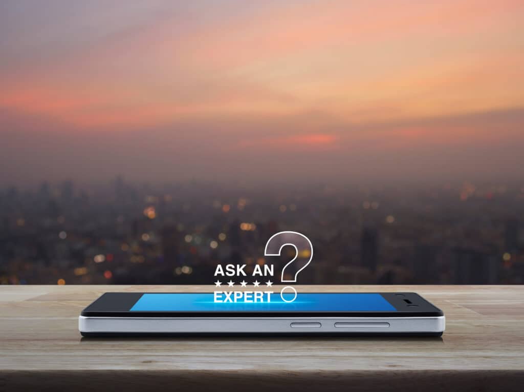 Business communication online concept Cell phone sitting on text and written text "Ask an Expert"